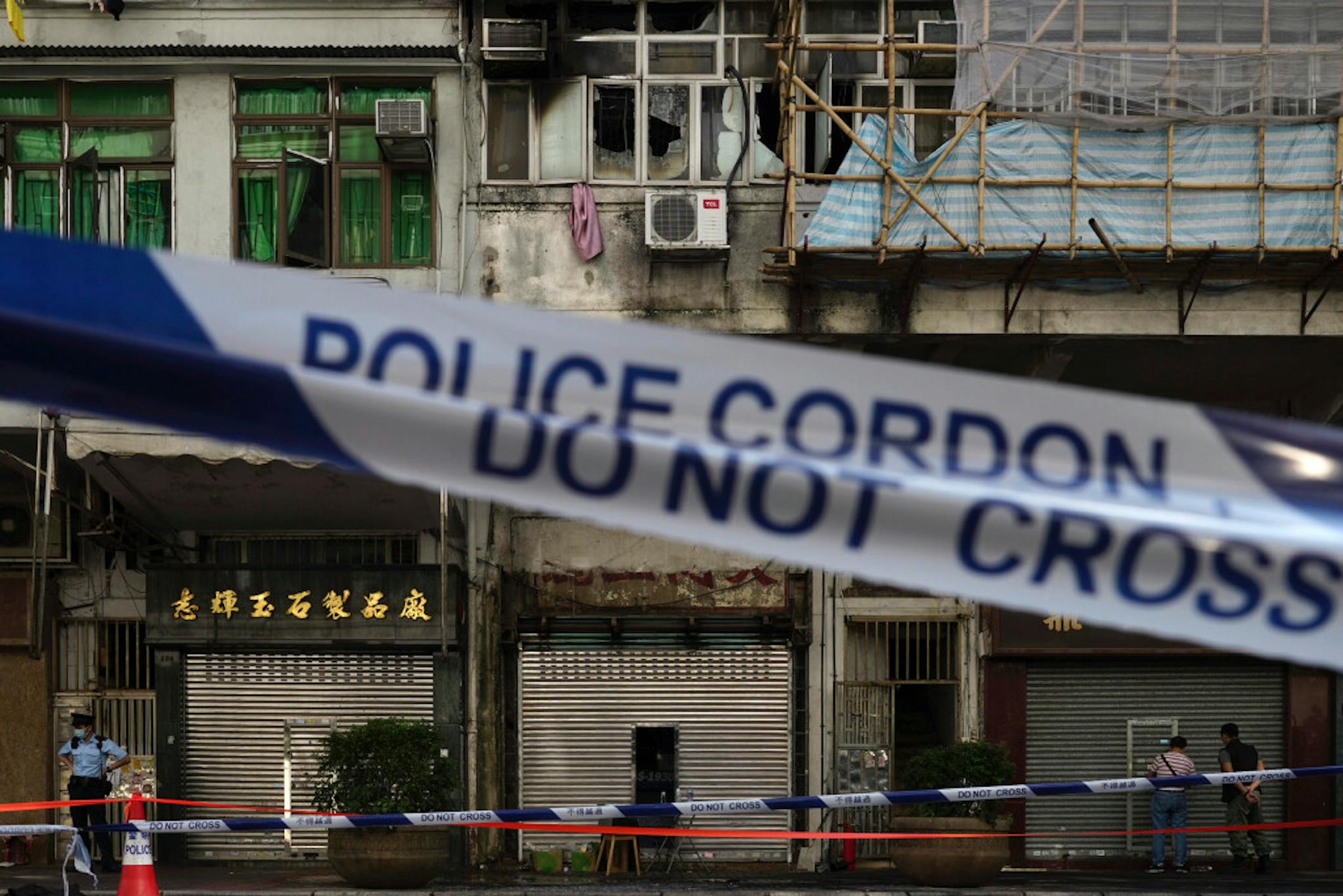 A police cordon line is set at a fire site, top center with broken windows, in Hong Kong Monday, Nov. 16, 2020. City authorities said a fire in a crowded residential district in Hong Kong has "caused a number of deaths and injuries."