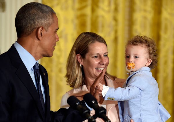 President Barack Obama, left, gets a high five from Oliver Reeve, right, the son of Minnesota Lynx coach Cheryl Reeve, center, in the East Room of the