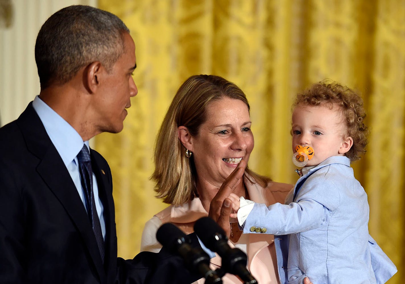 President Barack Obama, left, gets a high five from Oliver Reeve, right, the son of Minnesota Lynx coach Cheryl Reeve, center, in the East Room of the White House in Washington, in 2016.