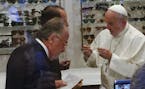 In this picture taken Thursday, Sept. 3, 2015, Pope Francis tries on a pair of spectacles in an eyeglass store in via del Babuino, in central Rome. Po