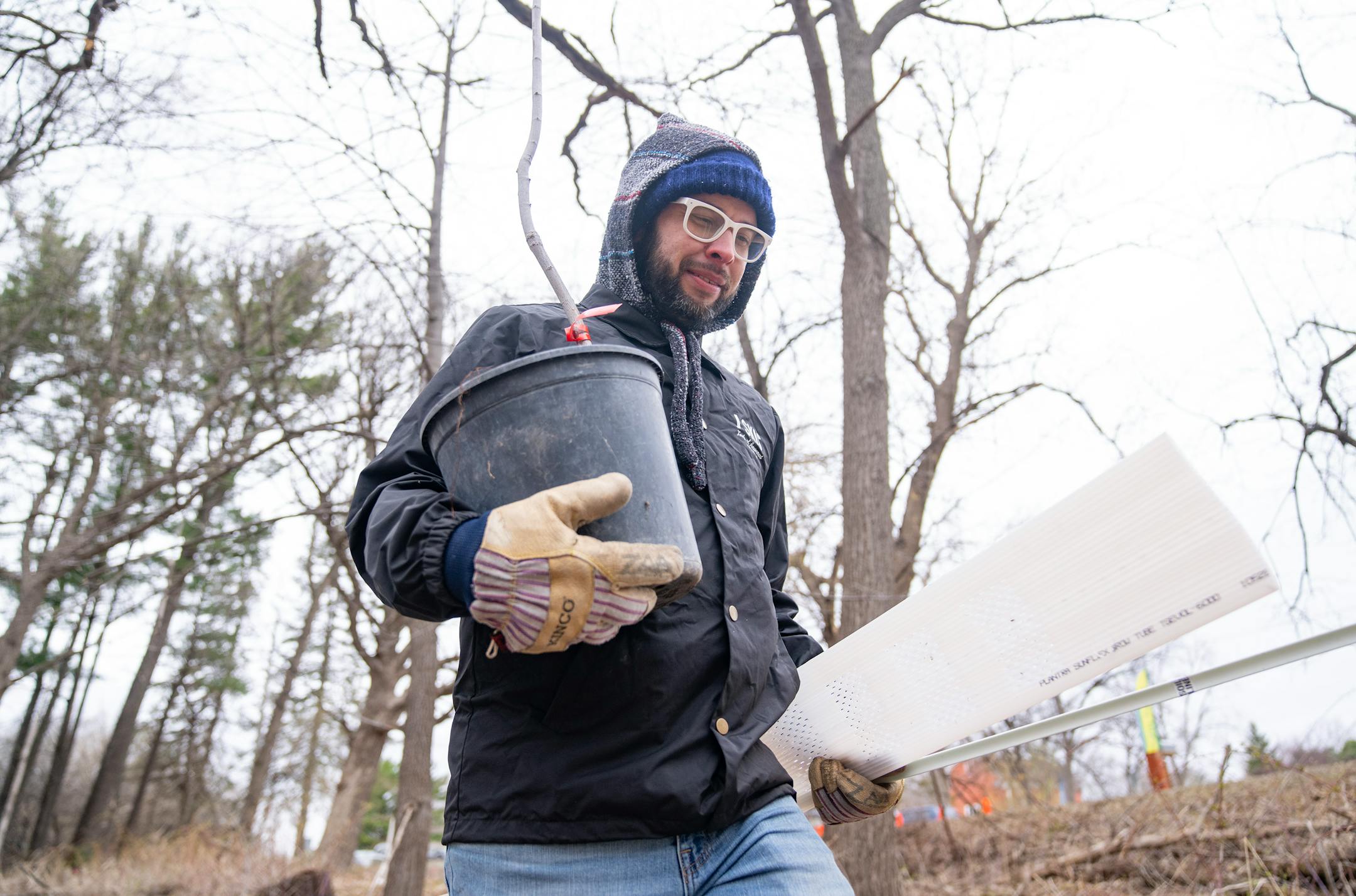 Zach Anderson carries an elm tree to be planted as part of a tree planting event Saturday, April 22, 2023, on a Nature Hiking Trail leading to the Minnesota River in Bloomington.