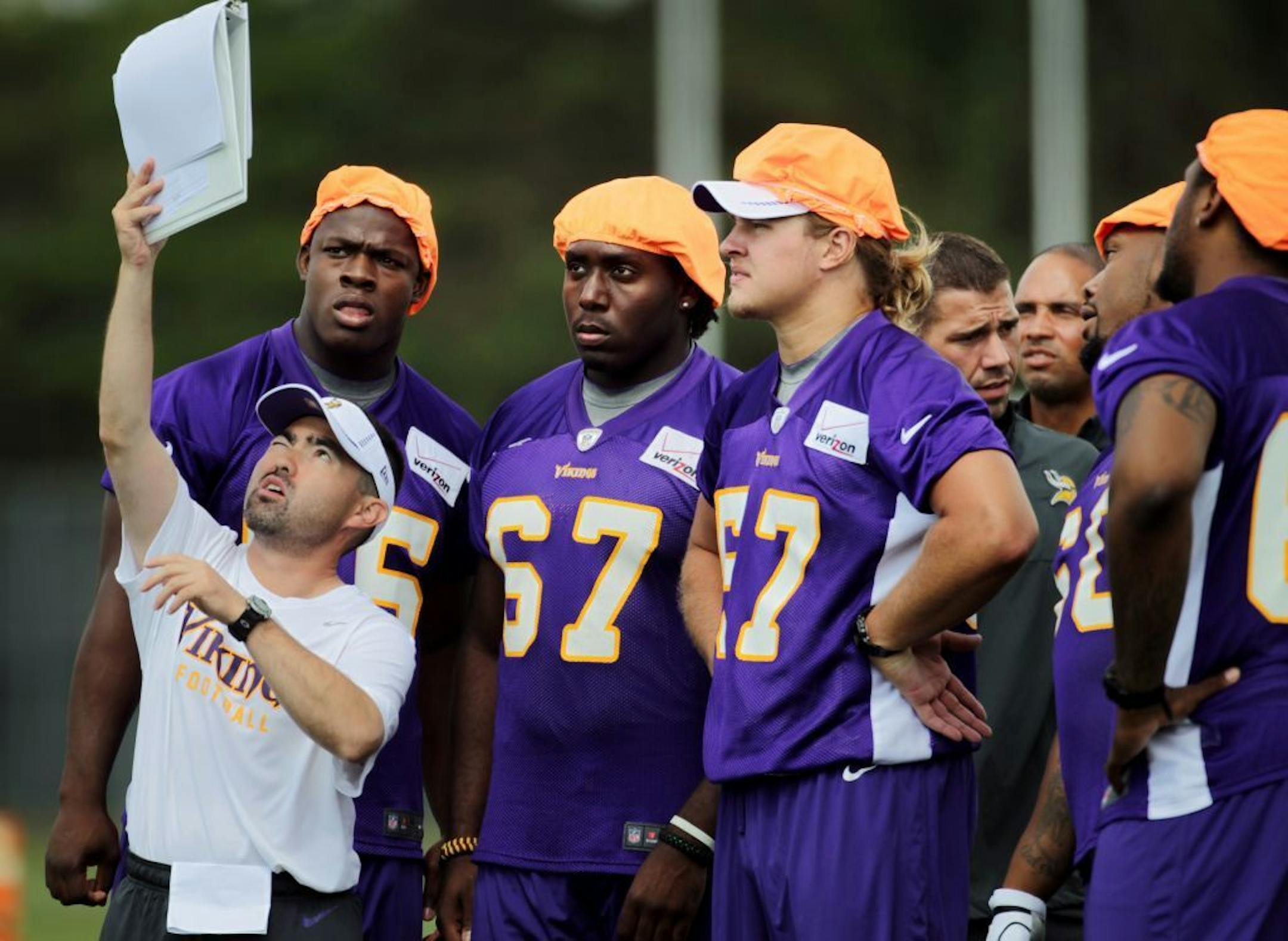 Jeff Imamura defensive assistant held up plays for the defense players Ernest Owusu left, Austin Pasztor, and and Audie Cole during first day of practice at Minnesota State University, Mankato Friday July 27, 2012 Mankato ,MN .