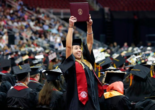 Emma O'Donoghue holds up her diploma as she returns to her seat during an undergraduate commencement ceremony for Ramapo College in Newark, N.J., Thur