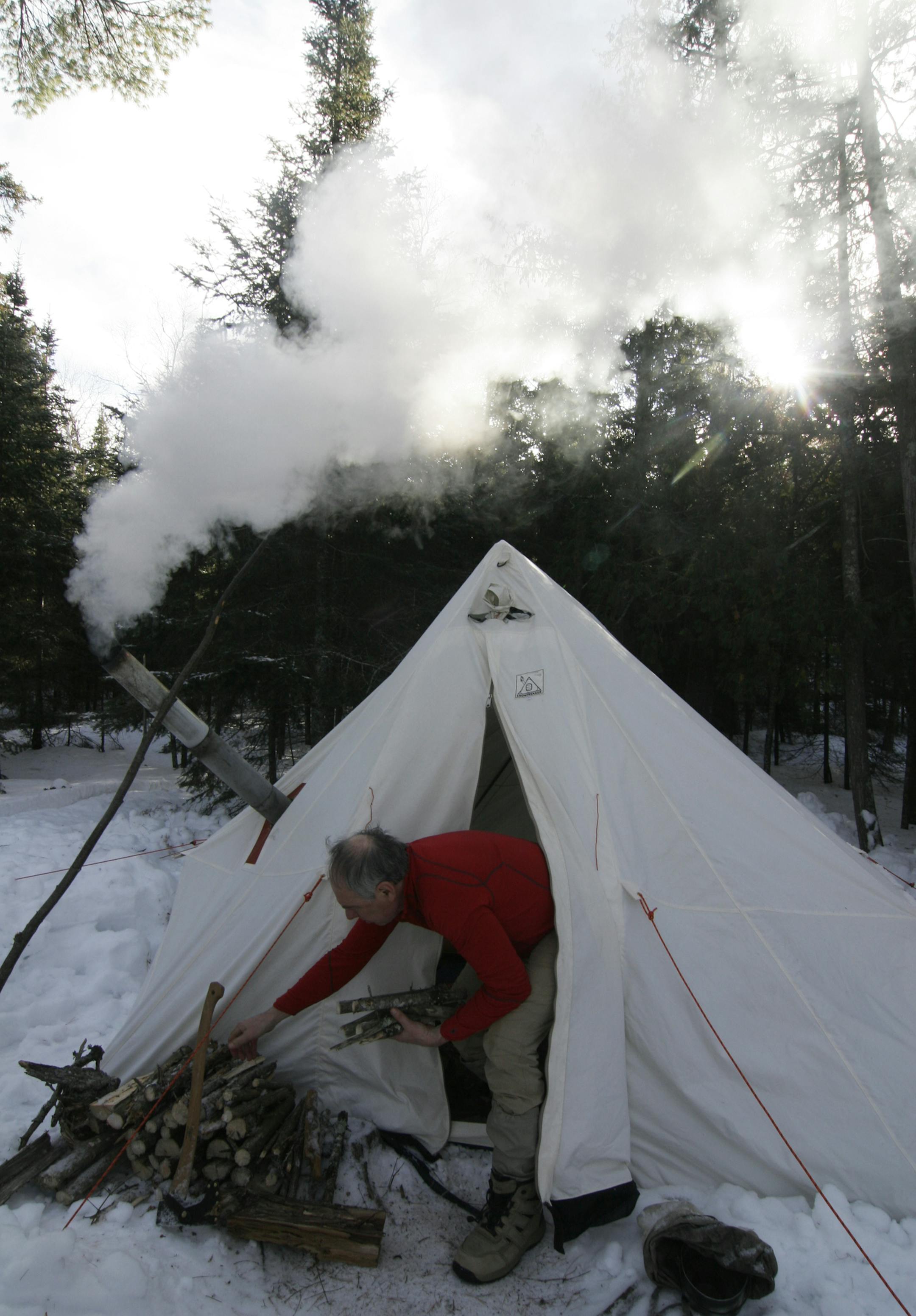 Steve Piragis of Ely grabs some wood for the stove heating his canvas tent. The large 10-by-15-foot tent gave four campers room to sleep, eat and store gear.