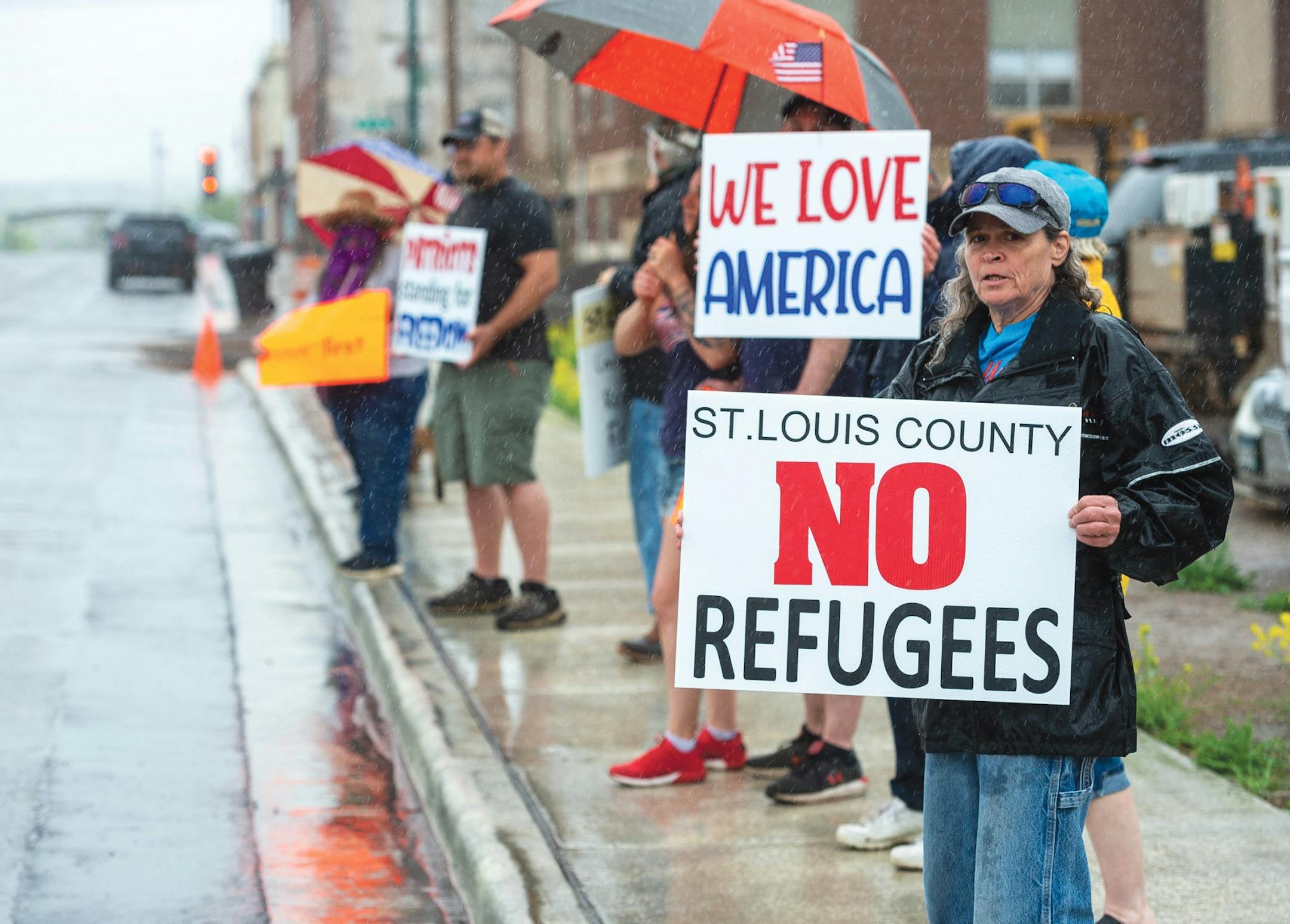 Dozens of protesters stood in the rain Tuesday morning outside St. Louis County’s government services building in Virgnia, Minn.