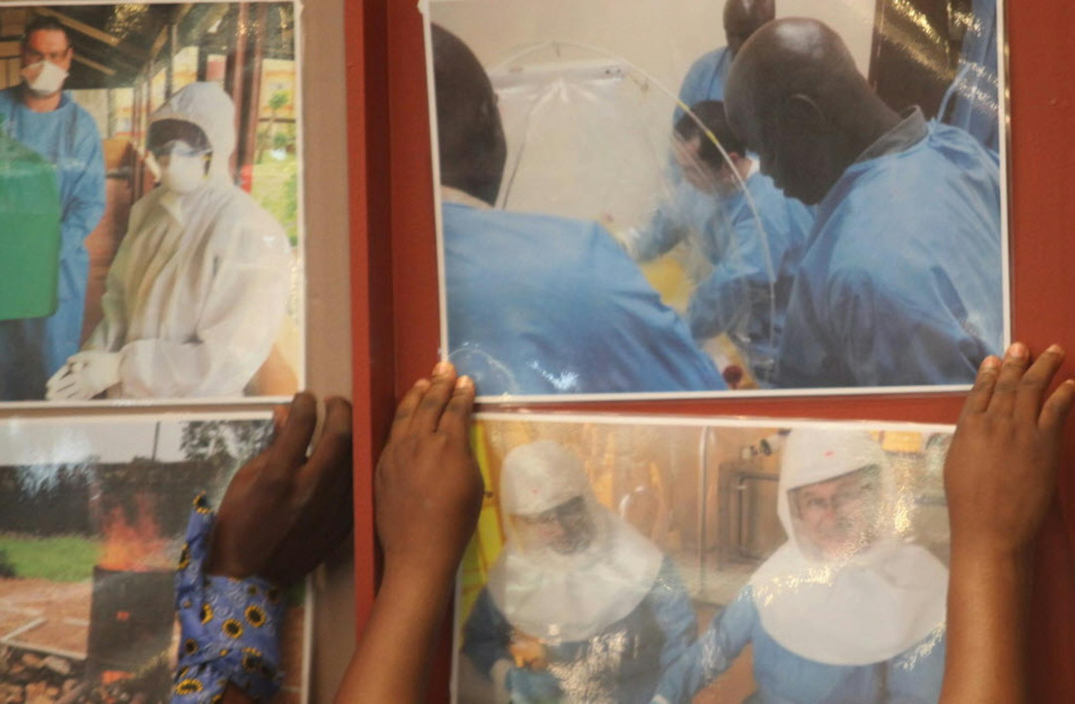 Delegates attending an Ebola preparedness conference in Johannesburg, Friday, Oct. 10, 2014, prior to a news conference in Johannesburg, paste enlarged photos of health workers at work in affected west African countries. Health officials discussed ways of tackling Ebola should the disease enter South Africa as well as the assistance by South Africa to affected countries. (AP Photo/Denis Farrell)