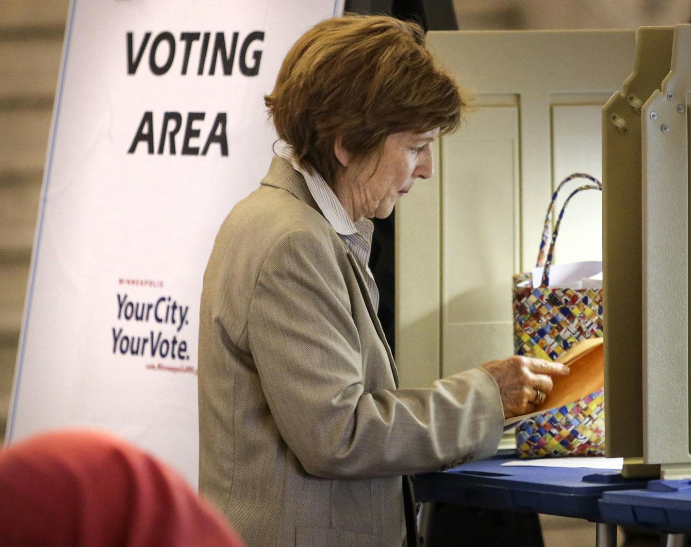 Jane Mauer of Minneapolis, who will be out of town on voting day, places her ballot in an envelope after completing her first absentee ballot ever at the Minneapolis City Hall Friday, Aug. 8, 2014, in Minneapolis, MN.] (DAVID JOLES/STARTRIBUNE) djoles@startribune A heated primaries have drawn an outpouring of absentee ballots in the first race where voters are being encouraged to vote early through the new no excuses absentee rules.**Jane Mauer,cq ORG XMIT: MIN1408081903364263