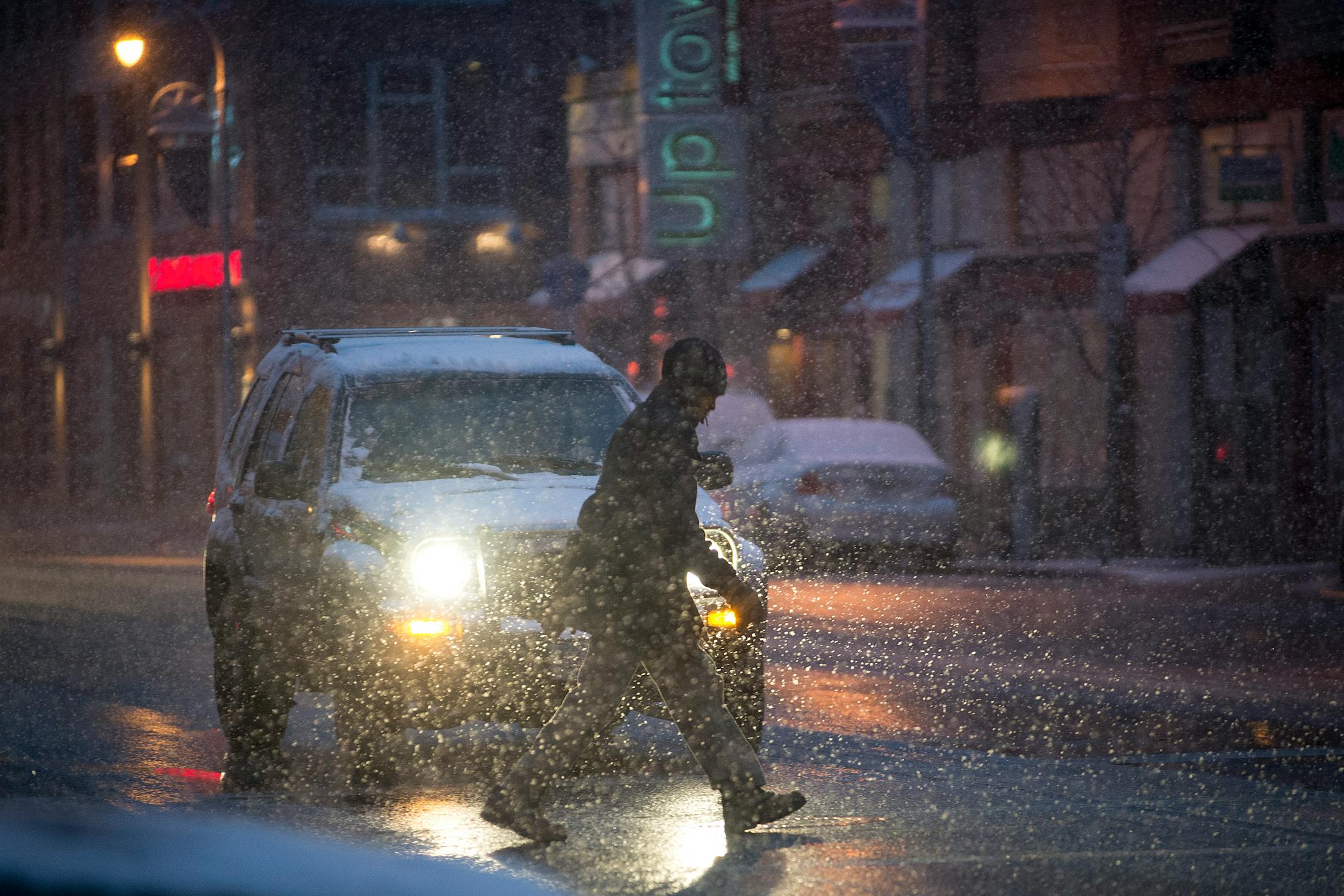 A man crossed the street at Lyndale Avenue and Lake Street during heavy snow fall on Sunday night.