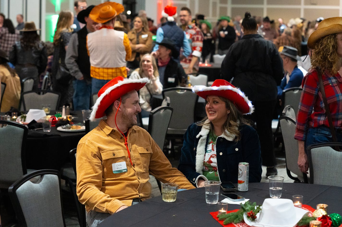 Chris McLey, a manager at Ryan Companies, and Angie Laschinger laugh together at the Ryan Companies' western-themed holiday party in Brooklyn Center, Minn. on Friday, Dec. 1, 2023. In a post-pandemic rise of the company holiday party, over 800 guests were invited to eat, drink and dance the night away. ] Angelina Katsanis • angelina.katsanis@startribune.com