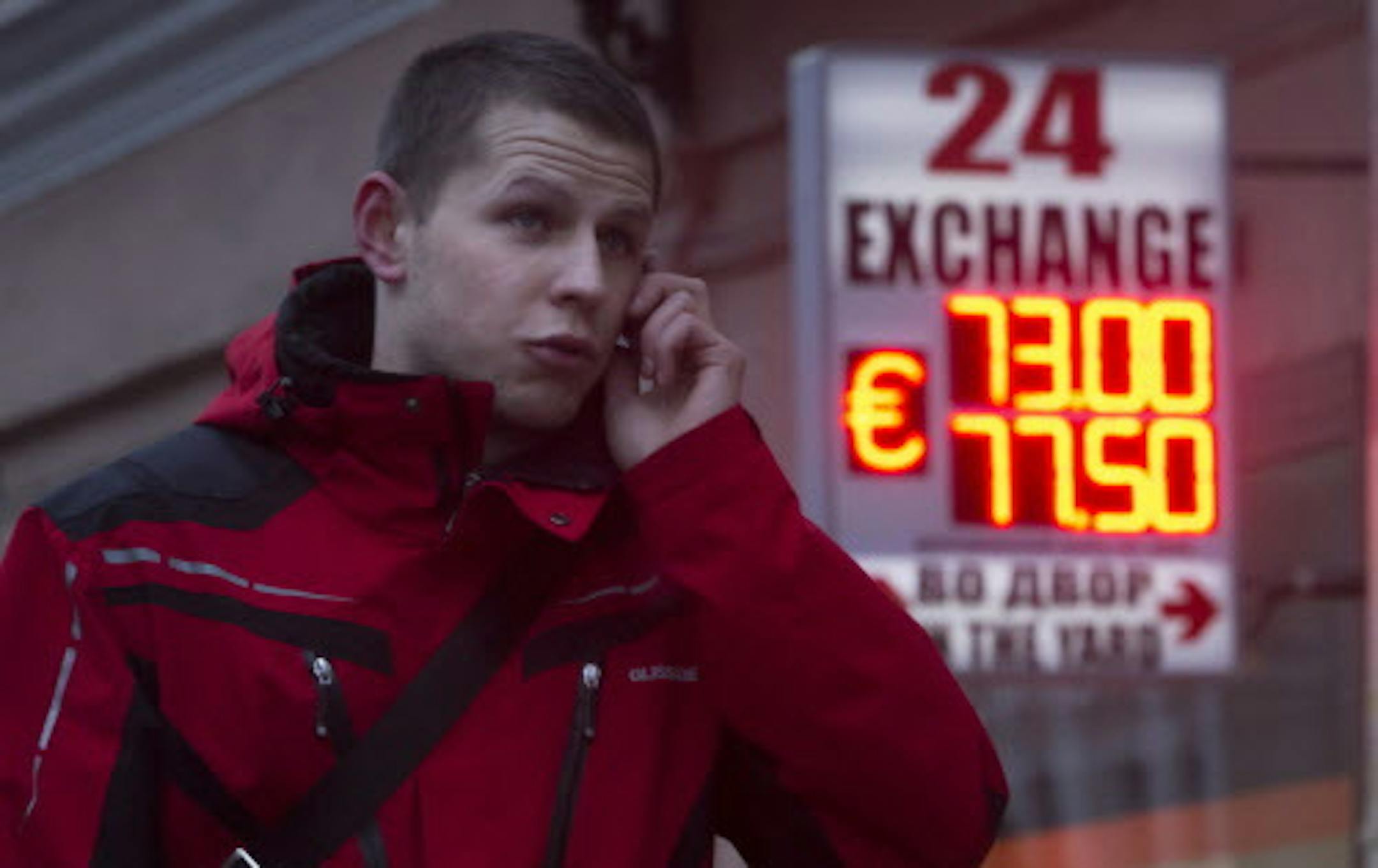 A man uses a mobile phone outside a display of a currency exchange office in St.Petersburg, Russia, Tuesday, Jan. 27, 2015. A day after a top ratings agency cut Russiaís rating to junk level, the government in Moscow on Tuesday announced a plan that will see the economy return to a budget surplus in 2017. Standard & Poorís downgraded Russiaís rating to BB-plus late on Monday, a non-investment grade, for the first time since 2004, citing a slide in the ruble and weakening revenue f