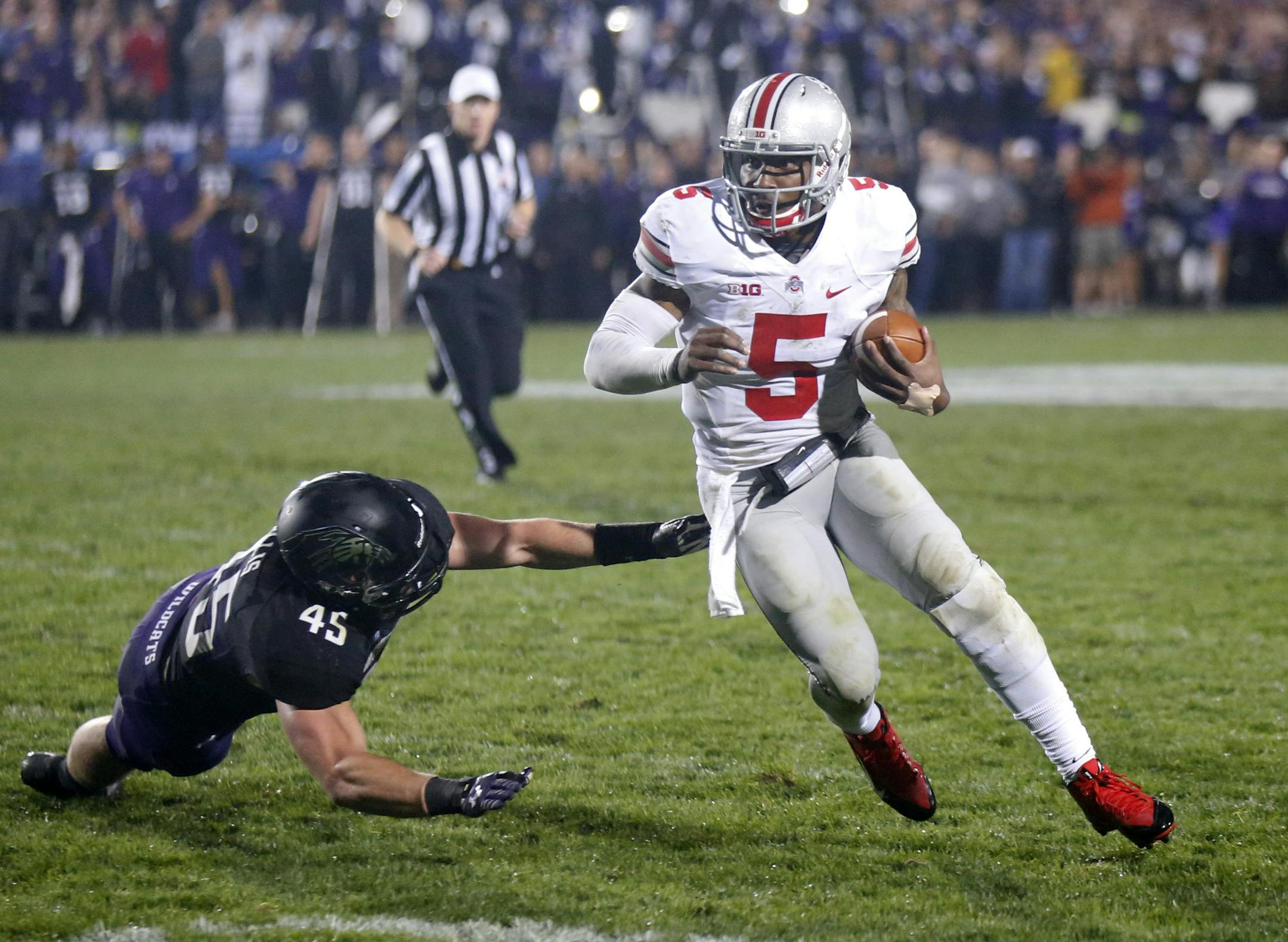 In this photo taken on Saturday, Oct. 5, 2013, Ohio State quarterback Braxton Miller (5) runs past the outstretched hands of Northwestern linebacker Collin Ellis (45) during the second half of an NCAA college football game in Evanston, Ill. Ohio State plays their next game at home against Iowa on Oct. 19. (AP Photo/Charles Rex Arbogast) ORG XMIT: MIN2013101019532288