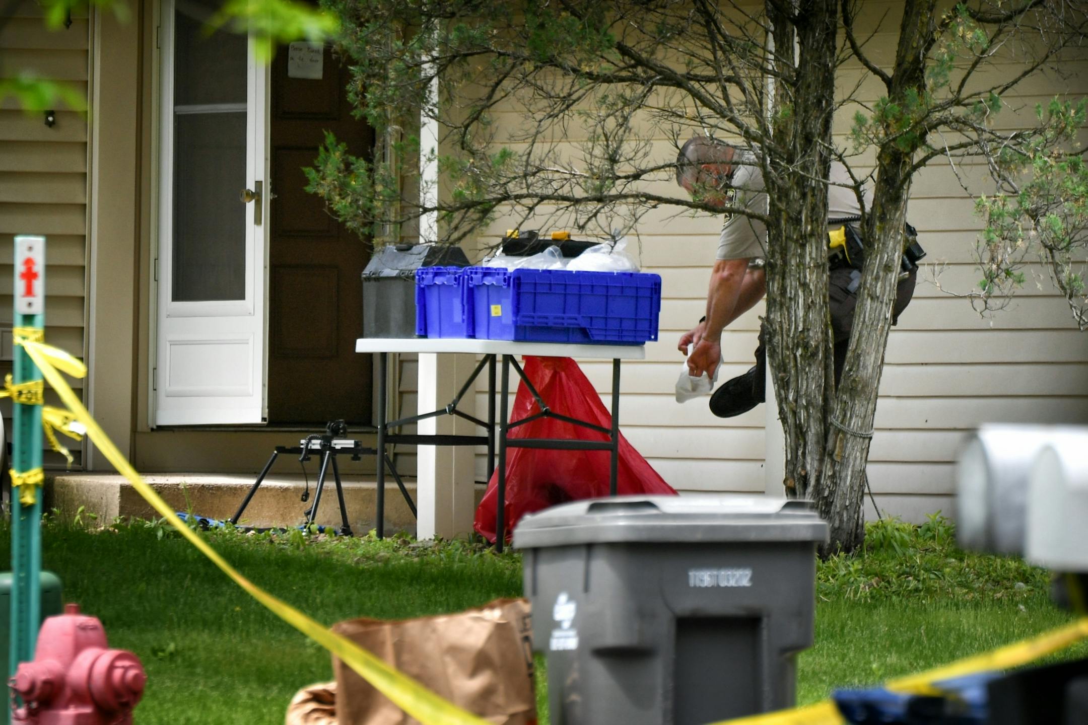 A Hennepin County Sheriff's investigator put on protective footwear before entering the home in which two bodies were found Thursday morning.