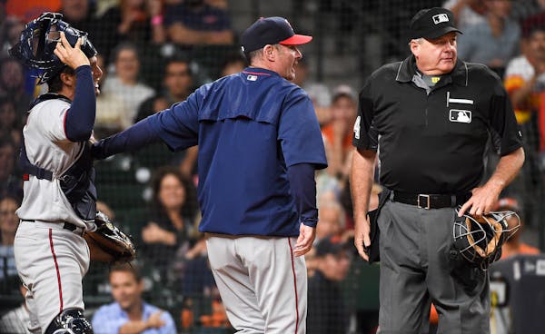 Minnesota Twins manager Paul Molitor, center, holds back catcher John Ryan Murphy, left, after home plate umpire Jerry Lane, right, threw out Murphy i