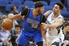 Dallas Mavericks' Seth Curry, left, keeps the ball at a safe distance from Minnesota Timberwolves' Ricky Rubio, of Spain, during the first half of an 