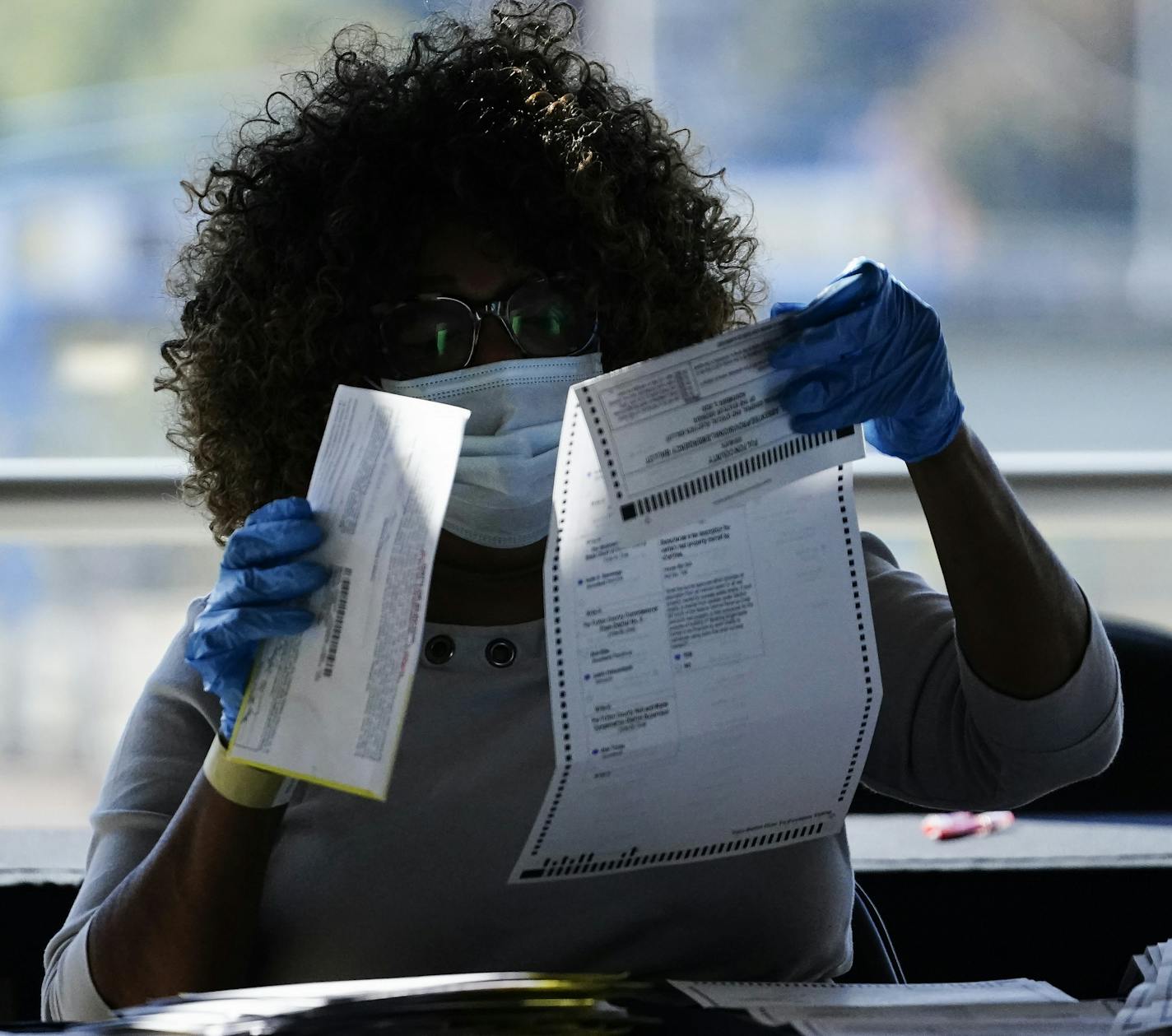 An election personnel examines a ballot as vote counting in the general election continues at State Farm Arena, Wednesday, Nov. 4, 2020, in Atlanta. (AP Photo/Brynn Anderson)