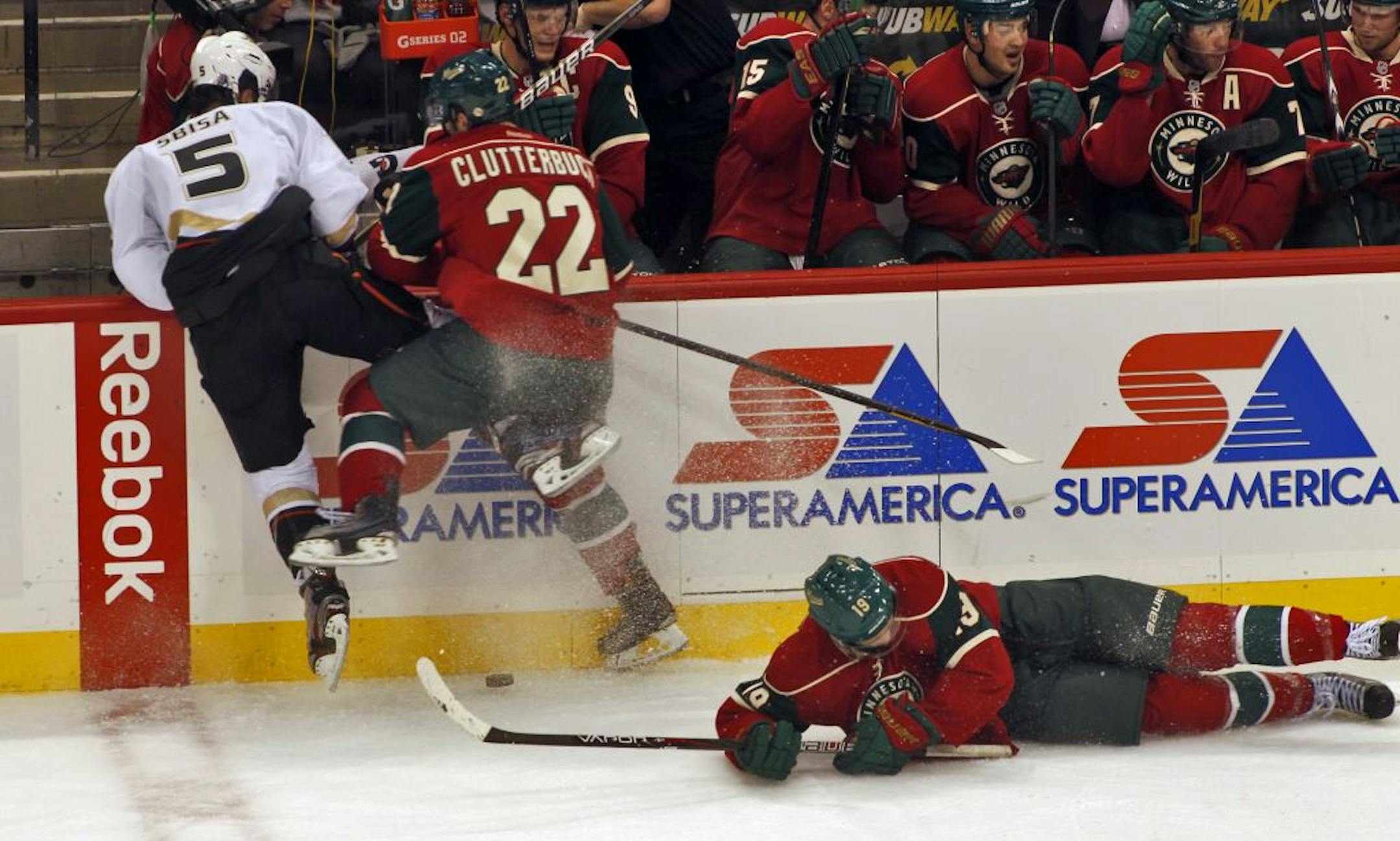 Anaheim's Luca Sbisa (5) and the Wild's Cal Clutterbuck (22) and Brett Bulmer (19) fought for control of the puck in third period action.