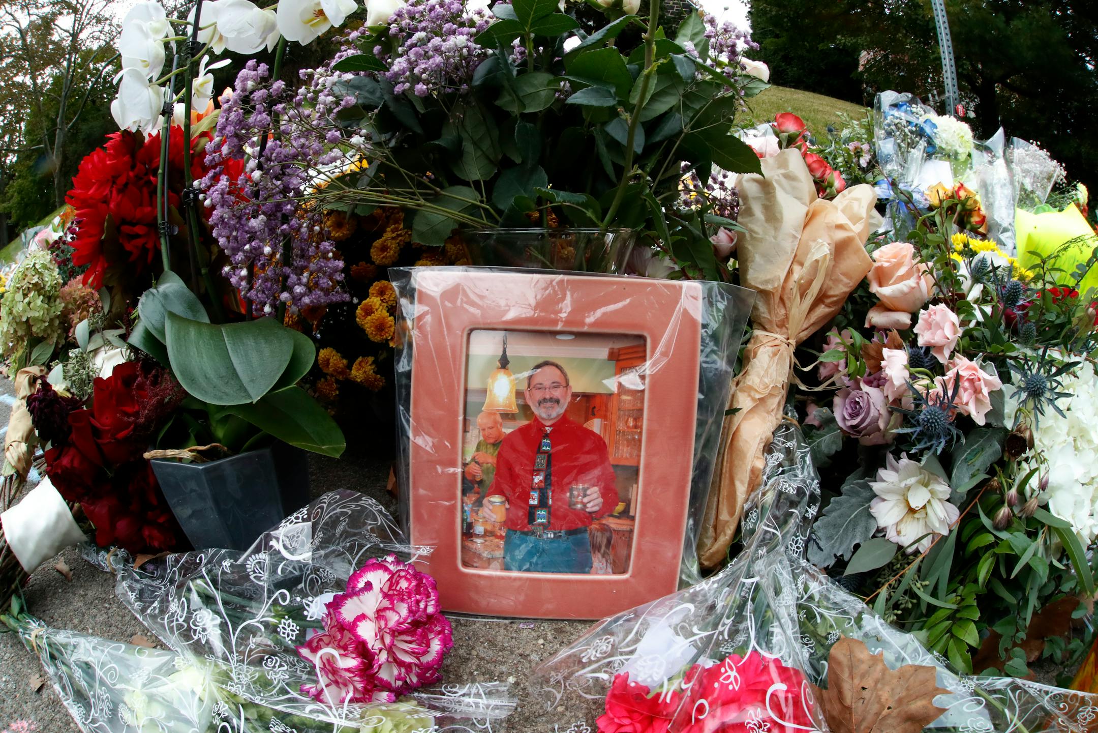 A photo of Tree of Life Synagogue victim Dr. Jerry P. Rabinowitz is surrounded Monday, Oct. 29, 2018, by flowers, part of a spontaneous memorial of flowers that has grown a block from the temple were he was killed when a shooter opened fire during worship services, killing 11, Saturday, Oct. 27, 2018 in Pittsburgh. (AP Photo/Gene J. Puskar)
