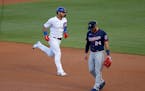 Chicago Cubs' Javier Baez, left, rounds the bases past Twins third baseman Josh Donaldson after Baez's home run during the first inning