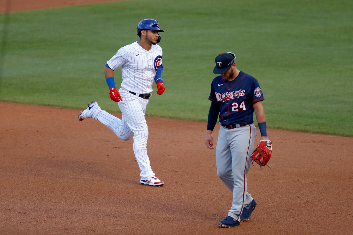 Chicago Cubs' Javier Baez, left, rounds the bases past Twins third baseman Josh Donaldson after Baez's home run during the first inning