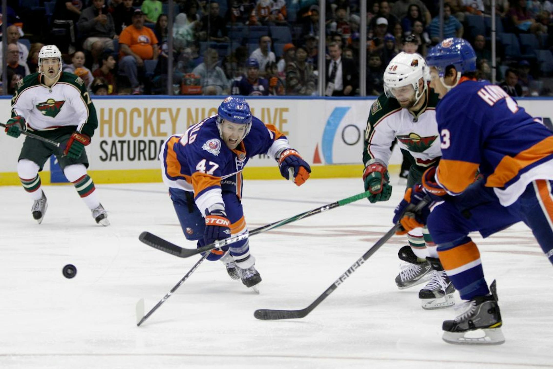 The Islanders' Andrew MacDonald struggled to get control of a loose puck as Wild left wing Guillaume Latendresse gave chase.