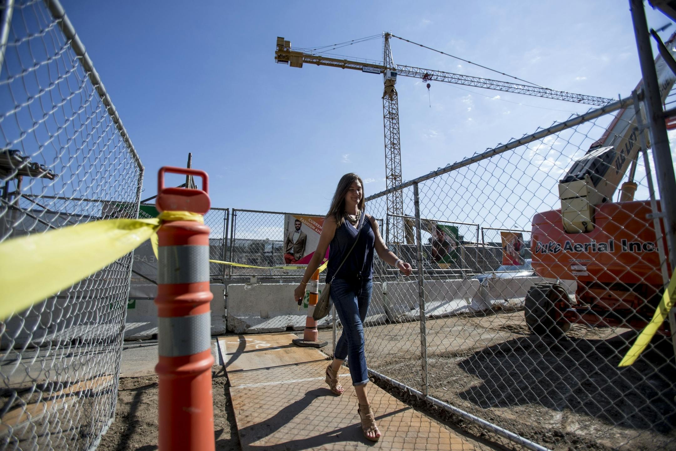 Alicia Place walks through the scaffolded pedestrian walkway towards the parking garage currently under construction.