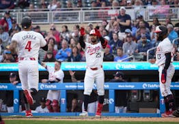 Twins outfielder Byron Buxton raises his hands to celebrate with shortstop Carlos Correa (4) as he crosses home plate in the first inning after a two-