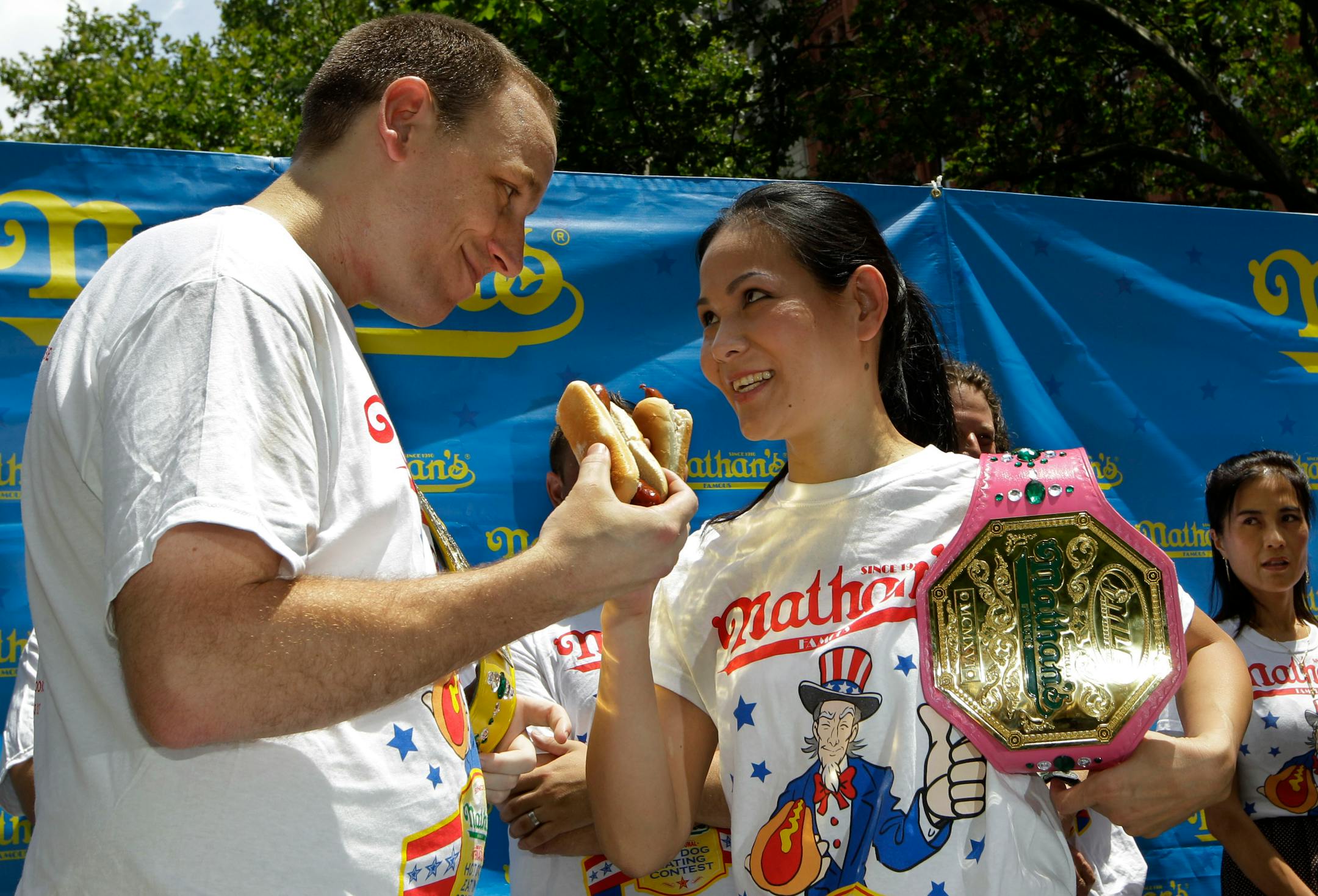FILE - In this Tuesday, July 3, 2012 file photo, five-time hot-dog eating world champion Joey Chestnut, left, and women's record-holder Sonya Thomas, center, face each other during a weigh-in for contestants in the annual Coney Island Fourth of July international hot-dog eating contest in New York. The two are due to defend their respective men�s and women�s titles in the 2013 competition. (AP Photo/Kathy Willens)
