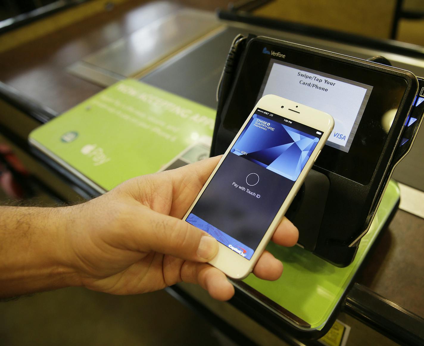 FILE - In this photo taken Friday, Oct. 17, 2014, Eddy Cue, Apple Senior Vice President of Internet Software and Services, demonstrates the new Apple Pay mobile payment system at a Whole Foods store in Cupertino, Calif. Apple on June 8, 2015 said that it&#xed;s adding store-issued credit cards and store rewards programs to Apple Pay, the mobile payments service it launched last fall. (AP Photo/Eric Risberg, File)