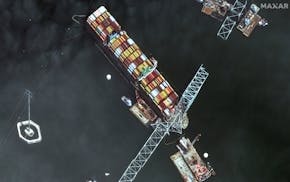 This satellite image provided by Maxar shows the bow of the container ship Dali remains stuck underneath sections of the fallen Francis Scott Key Brid