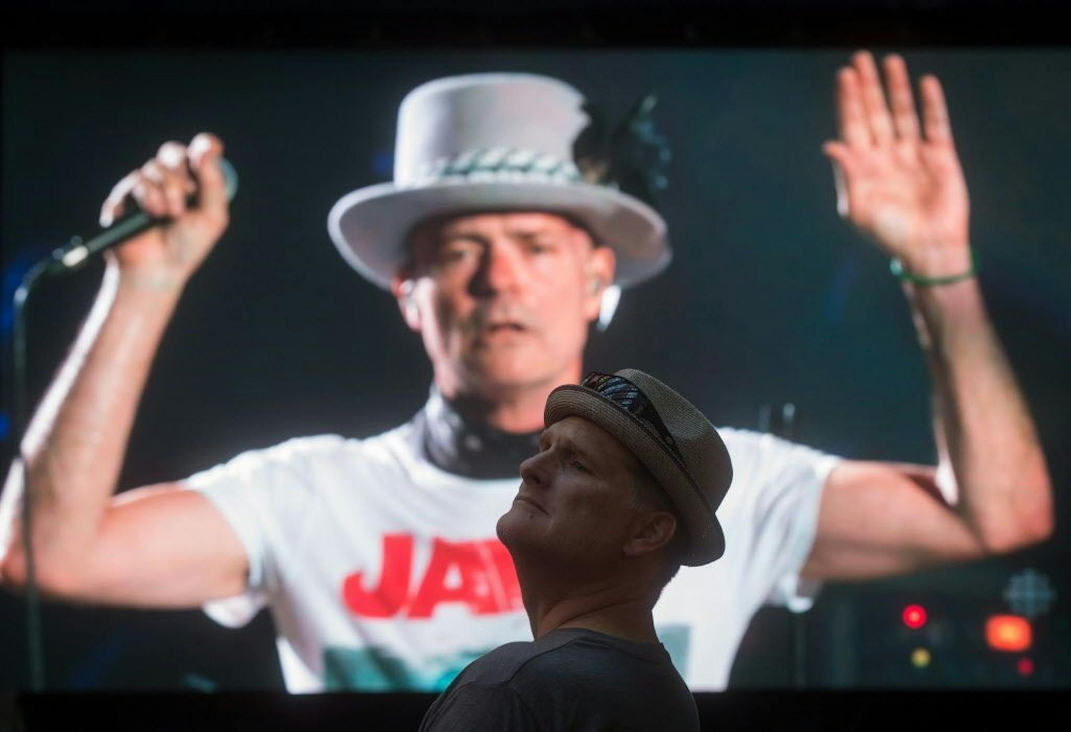 Lead singer Gord Downie is seen performing on a screen as a man watches during a viewing party for the final stop in Kingston, Ontario, from Vancouver, British Columbia, Saturday Aug. 20, 2016. The Tragically Hip mixed fan favourites, newer songs and some politics on Saturday night during the final show of their "Man Machine Poem" tour.