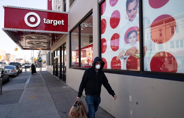 FILE - In this April 6, 2020 file photo, a customer wearing a mask carries his purchases as he leaves a Target store during the coronavirus pandemic, 
