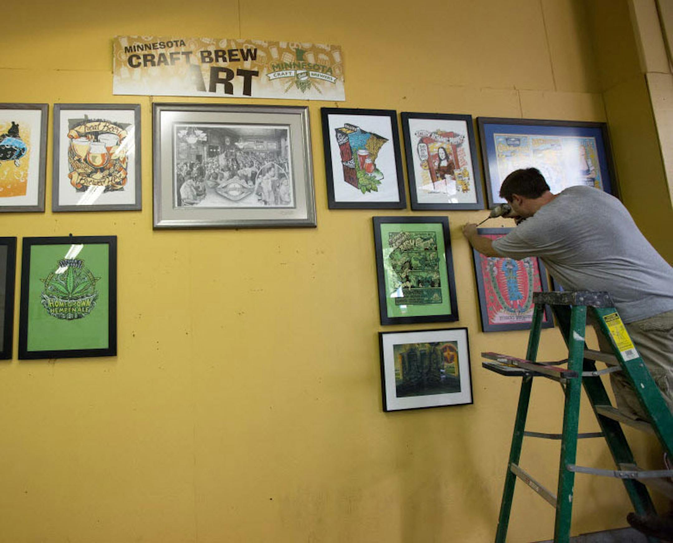 Travis Anderson hung Minnesota brewery art Monday at the Land of 10,000 Beers exhibit in the State Fair’s Agriculture/Horticulture building.