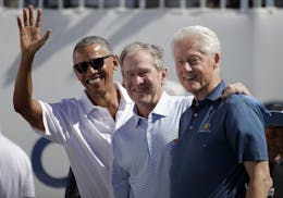 Former U.S. Presidents, from left, Barack Obama, George Bush and Bill Clinton greet spectators on the first tee before the first round of the Presiden