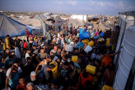 Palestinians displaced by the Israeli bombardment of the Gaza Strip queue for water at a makeshift tent camp in the southern town of Khan Younis, Mond
