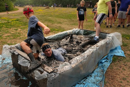 A runner lays full body in the first of the mud pits during the Minneswashta Mud Run Saturday, July 15, 2023 at Lake Minnewashta Regional Park in Chanhassen, Minn.