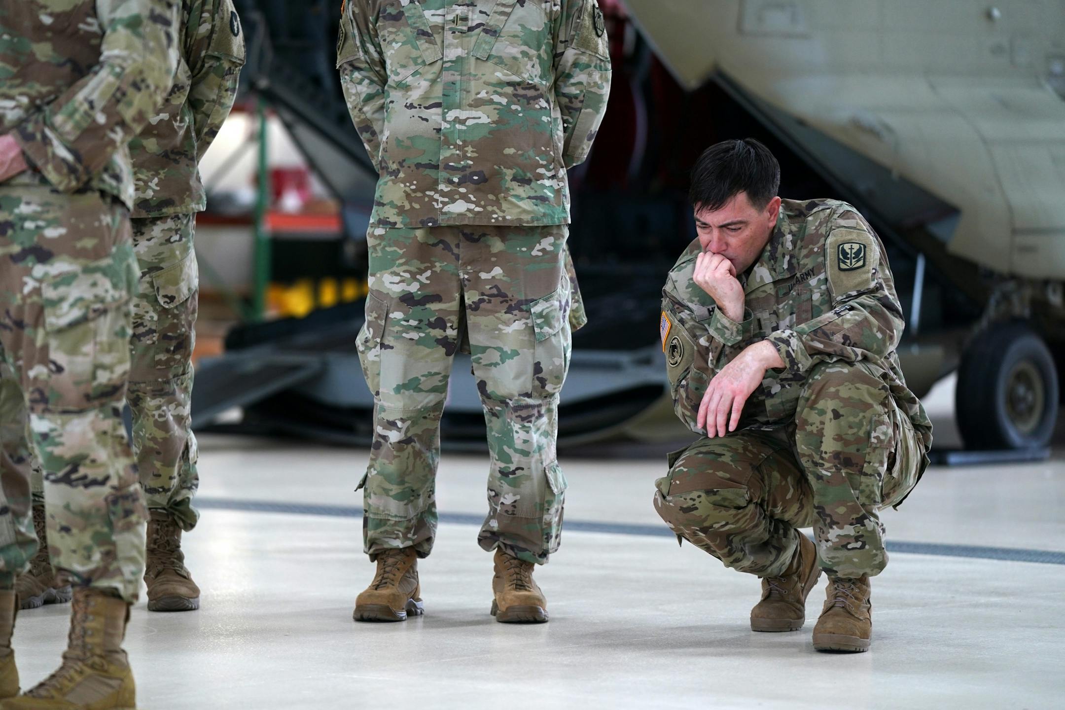 Chief Warrant Officer 5 Brad Husnik knelt as he listened along with his unit while Maj. Gen. Jon Jensen spoke during Saturday's press conference.