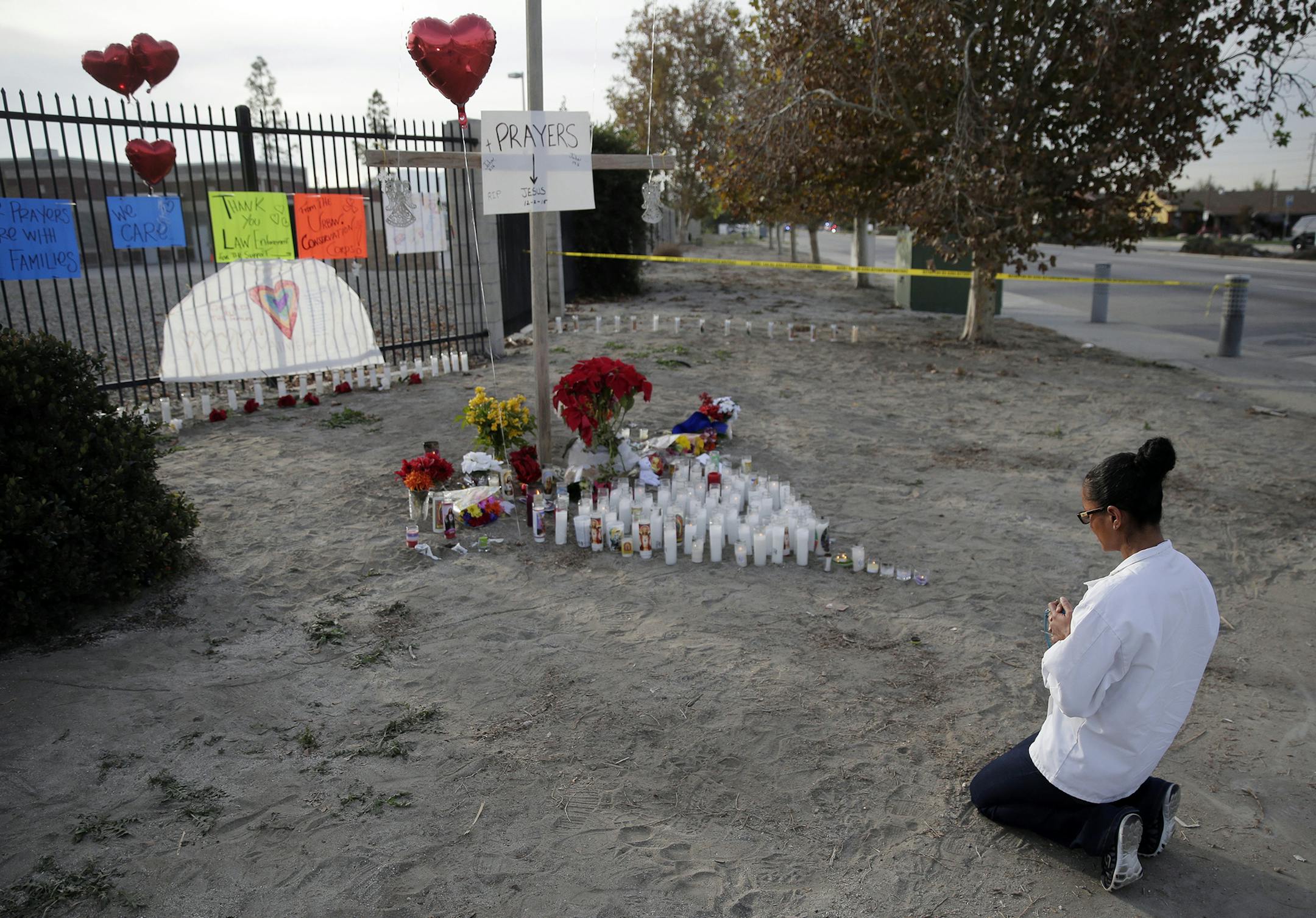 Melissa Smith prays at a makeshift memorial on Friday, Dec. 4, 2015, in San Bernardino, Calif. A husband and wife on Wednesday, dressed for battle and carrying assault rifles and handguns, opened fire on a holiday banquet for his co-workers, killing multiple people and seriously wounding others in a precision assault, authorities said. Hours later, the couple died in a shootout with police. (AP Photo/Chris Carlson) ORG XMIT: MIN2015120412330719