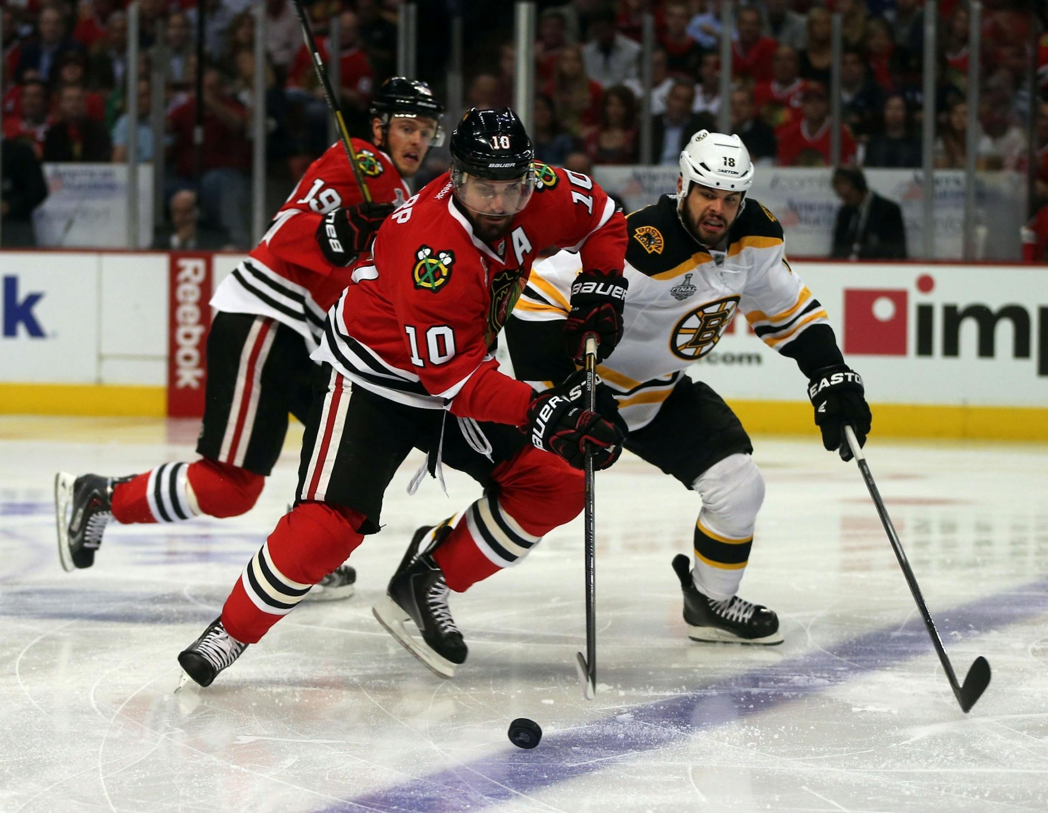 Patrick Sharp (10) carries the puck against the Boston Bruins' Nathan Horton, right, in the first period of Game 1 of the NHL Finals