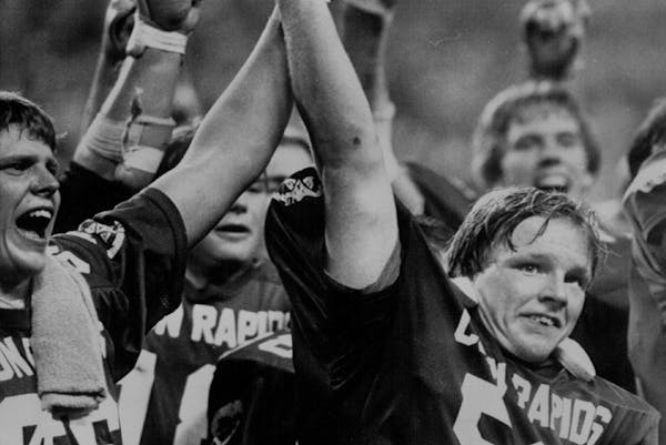 November 21, 1983 State Champs — Coon Rapids football team captain Adam Elliott (50) joins linebacker Jon Scott, left and other players Saturday nig