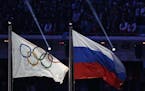 In this Feb. 23, 2014 file photo, the Russian national flag, right, flies after next to the Olympic flag during the closing ceremony of the 2014 Winte