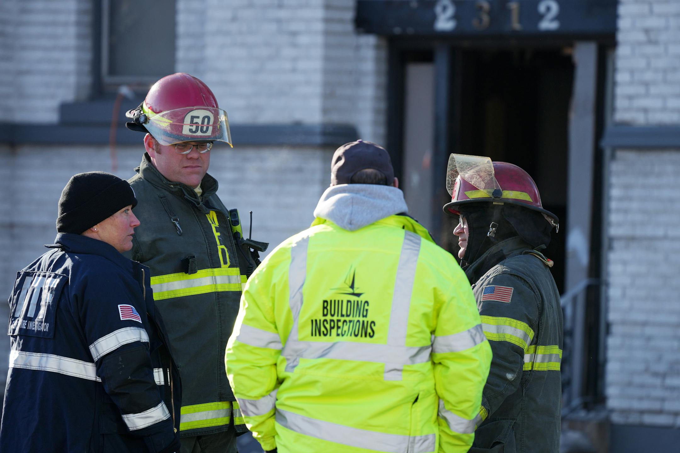 A member of the State Fire Marshal's office, an ATF agent, and Minneapolis fire fighters talk outside the scene of a building fire Saturday, Dec. 3, 2022 in the 2300 block of Lyndale Avenue South in Minneapolis.