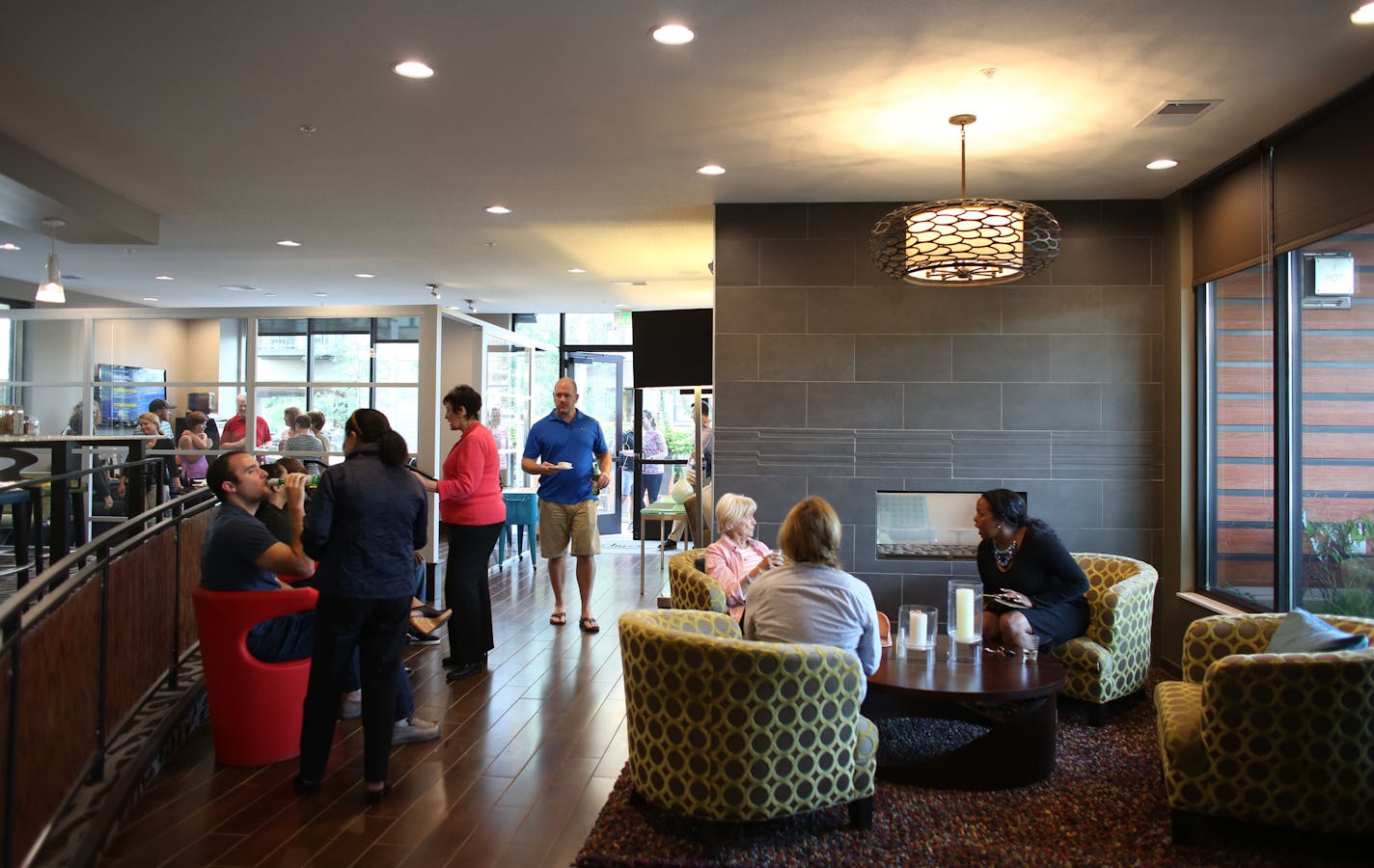 Residents chat with each other during a wine and cheese event held by e2 apartment complex in its community space. ] (KYNDELL HARKNESS/STAR TRIBUNE) kyndell.harkness@startribune.com Wine and cheese gathering for residents of e2 apartment complex in St. Louis Park Min., Wednesday September 2, 2015. "Third spaces," the public gathering spots in condo/apartment buildings that are getting more design attention as a way to attract buyers/tenants