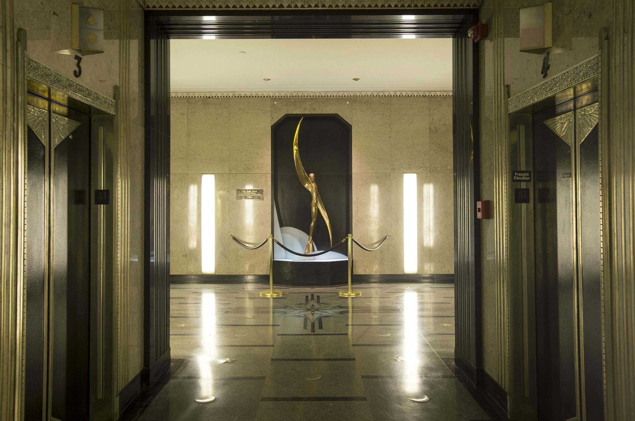 The Rand Tower's Art Deco lobby features moons and stars on the floor, a statue of "Flight" and zinc molding over the elevator doors.