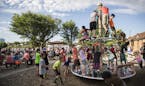 Children played on the playground equipment next to the large crowd watching the Johnny Holm Band perform on stage at the Summertime by George outdoor