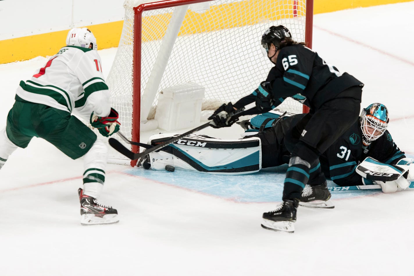 San Jose Sharks goaltender Martin Jones, on ice, and San Jose Sharks' Erik Karlsson (65) defend against a shot by the Wild's Zach Parise