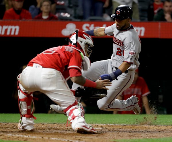 Minnesota Twins' Eddie Rosario, right, scores past Los Angeles Angels catcher Martin Maldonado on a hit by Jason Castro during the ninth inning of a b