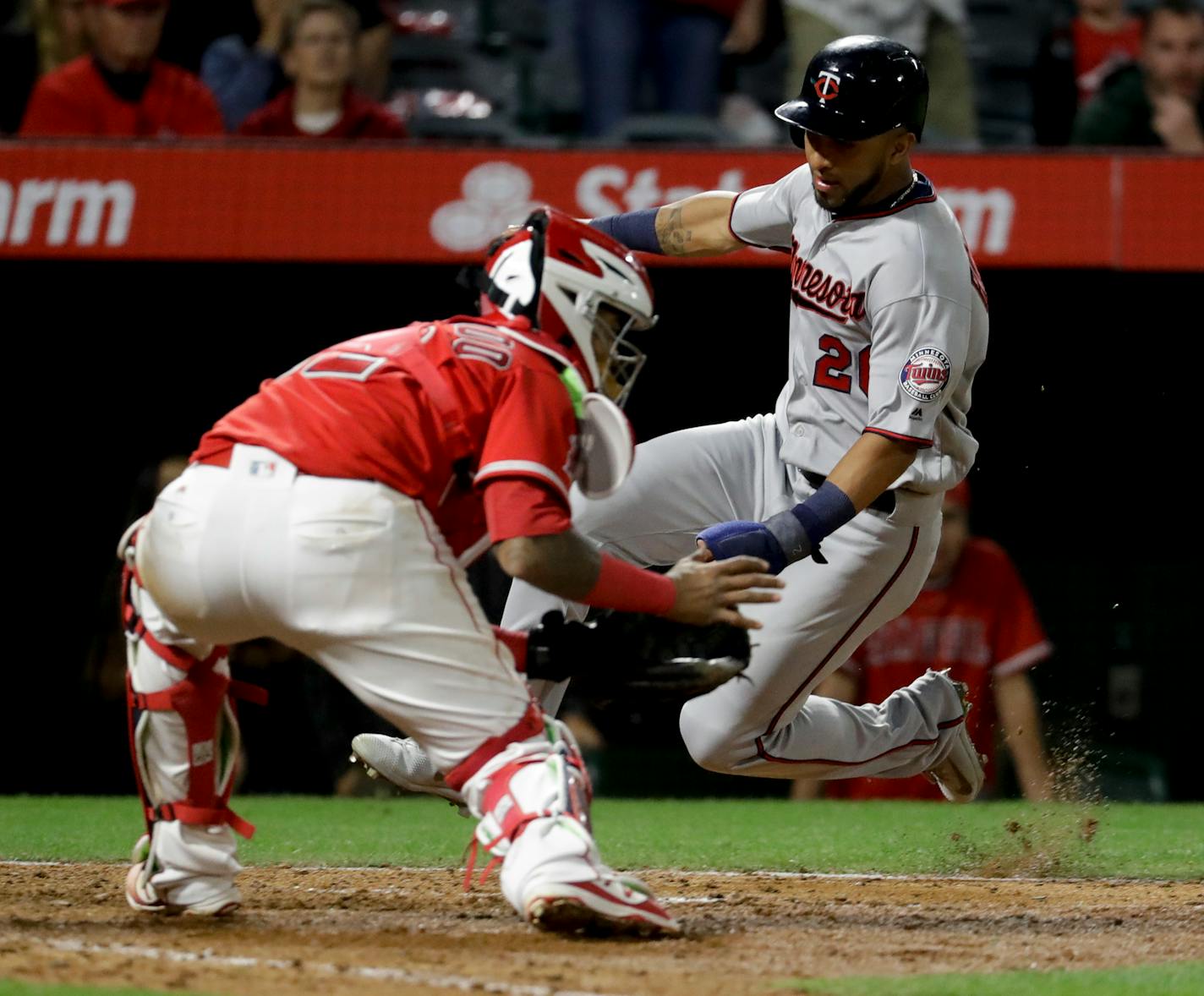 Minnesota Twins' Eddie Rosario, right, scores past Los Angeles Angels catcher Martin Maldonado on a hit by Jason Castro during the ninth inning of a baseball game in Anaheim, Calif., Thursday, June 1, 2017. (AP Photo/Chris Carlson)