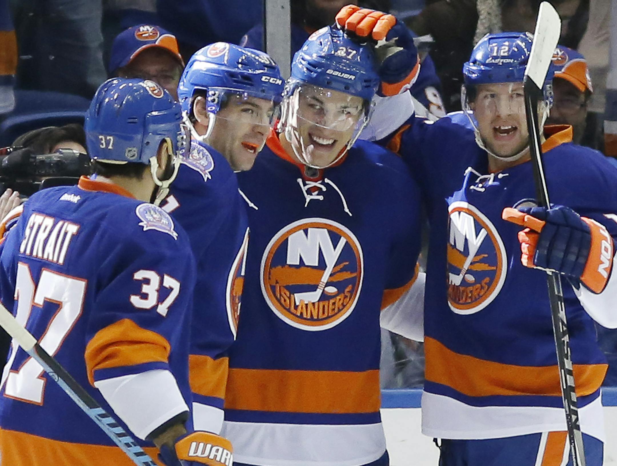 Teammates, including New York Islanders defenseman Brian Strait (37), Islanders center John Tavares (91) and Islanders left wing Josh Bailey (12) celebrate with Islanders center Anders Lee (27), who scored on Toronto Maple Leafs goalie Jonathan Bernier in the first period of an NHL hockey game at Nassau Coliseum in Uniondale, N.Y., Thursday, Feb. 12, 2015. (AP Photo/Kathy Willens)