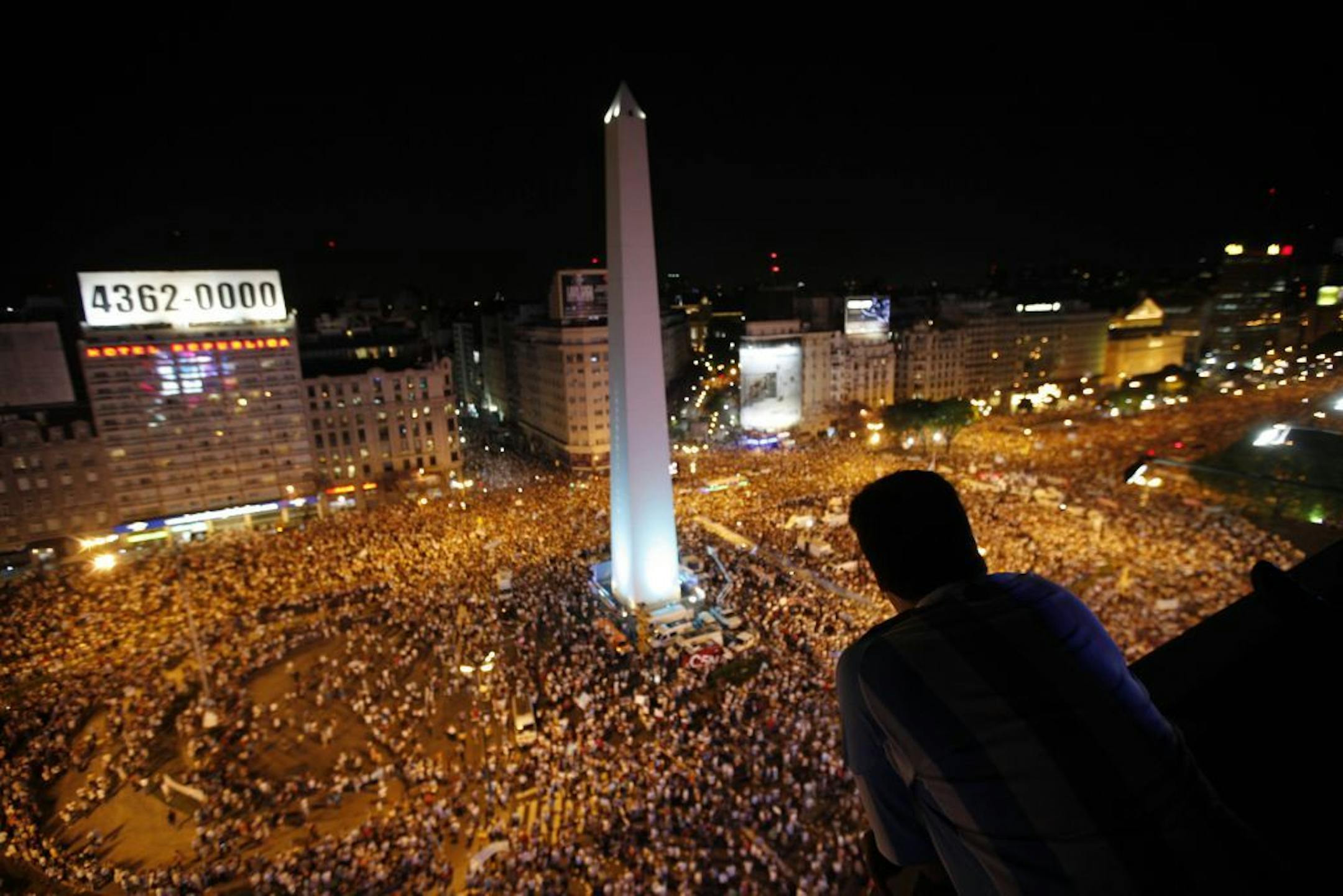 A man watches as protesters demonstrate during a march against Argentina's President Cristina Fernandez in Buenos Aires, Argentina, Thursday, Nov. 8, 2012. Angered by rising inflation, violent crime and high-profile corruption, and afraid Fernandez will try to hold onto power indefinitely by ending constitutional term limits, the protesters banged pots and marched on the iconic obelisk in Argentina's capital. Protests also were held in plazas nationwide and outside Argentine embassies and consul