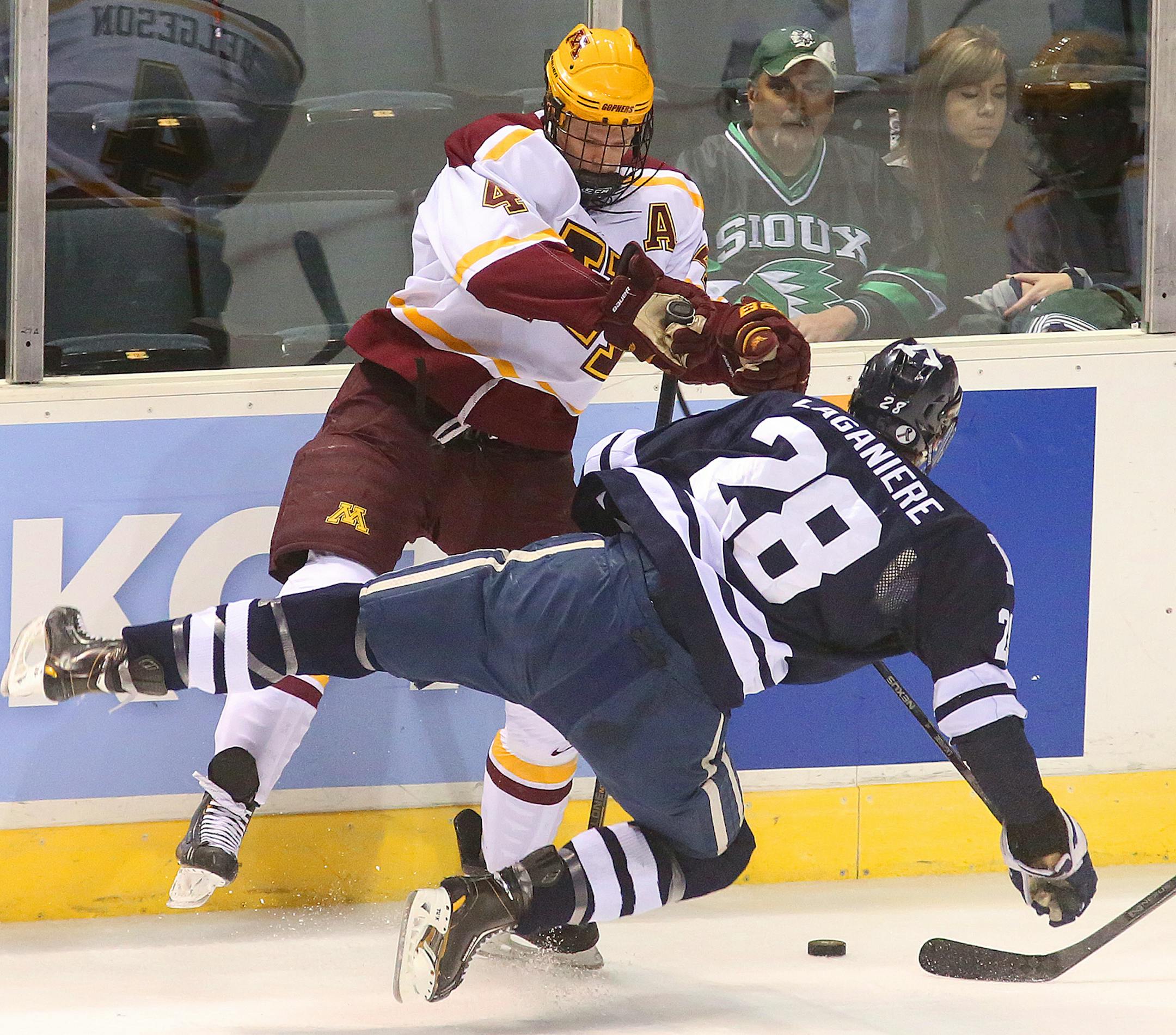 Minnesota's Seth Helgeson, left, and Yale's Antoine Laganiere collide while going after the puck during the scoreless first period of the Western Regional semi final at the Van Andel Arena in Grand Rapids Arena. ( Rex Larsen photo )